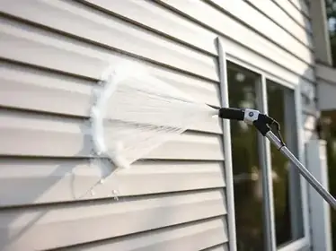 Soft washing a home exterior siding gently with specialized equipment